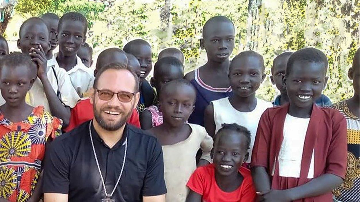 Bishop Christian sits with young African children