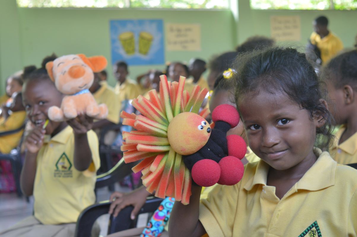 Girl in school A young girl at Santa María de los Cayapas Fiscal Unit holds a hand puppet and smiles brightly at the camera
