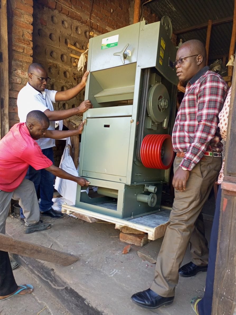 A large milling machine is delivered to Lirangwe. Several men move the machine into the building.