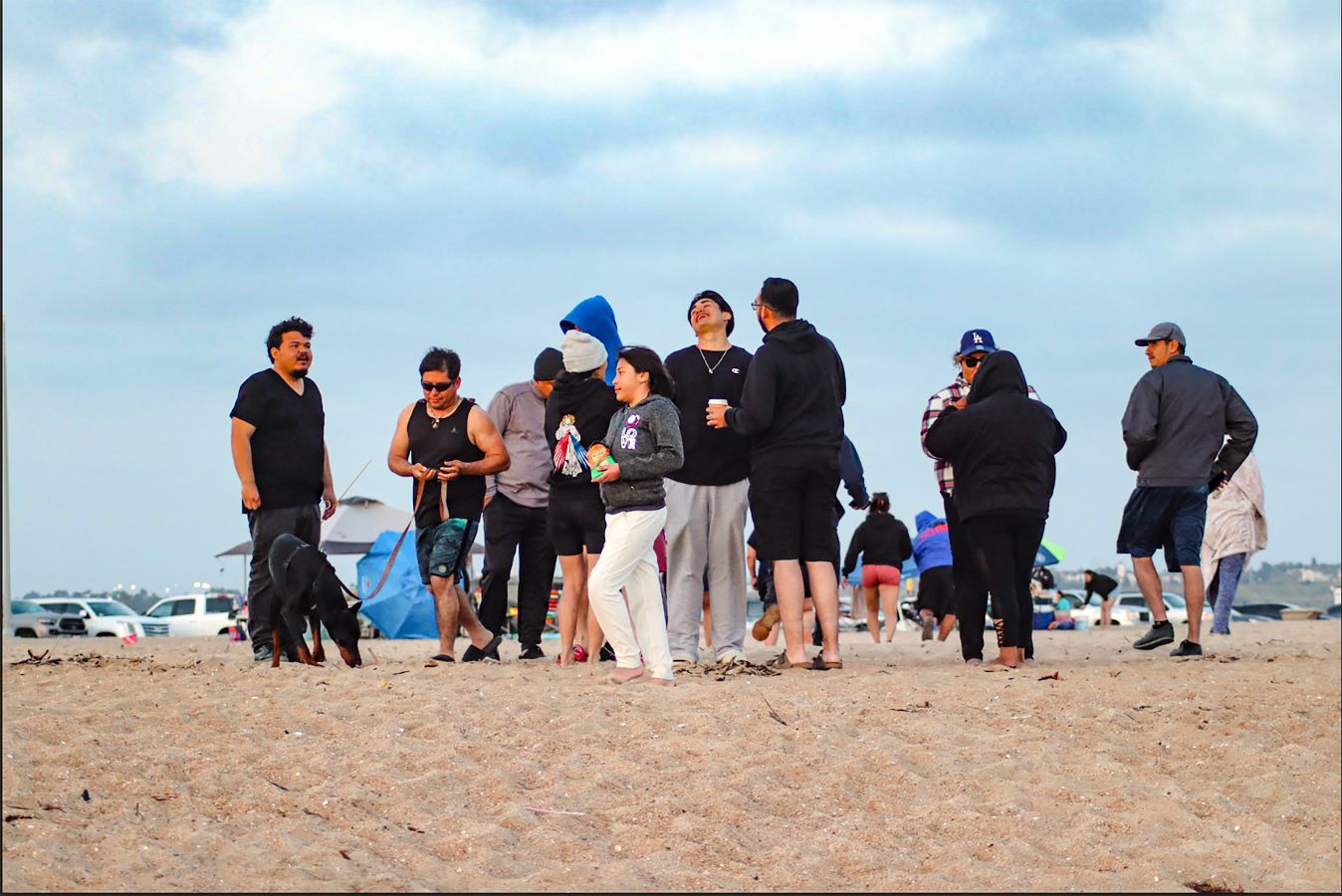 Members of the Missionary Souls young adult ministry gather on the beach. A bright blue sky behind them.