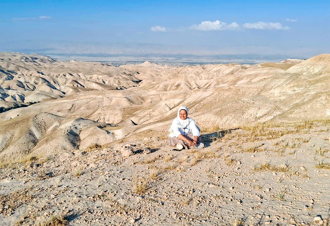Sister Cecilia sit on the sand in Israel/Paletsine