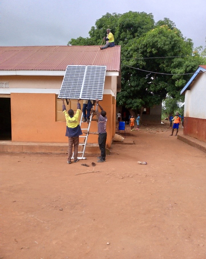 A large solar panel is lifted onto a single story school building