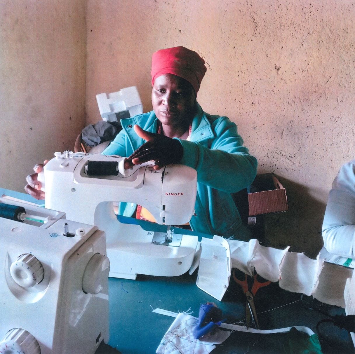 A young, South African mother practices sewing items on a sewing machine.