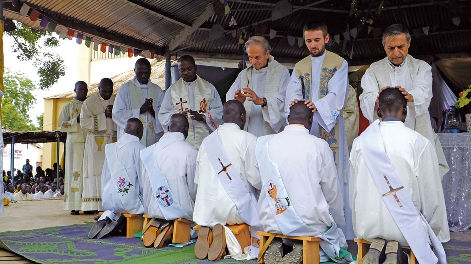 Young men kneel to receive the sacrament of ordination